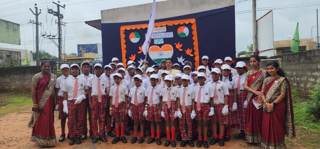 Students and teachers posing in front of Independence Day stage decoration