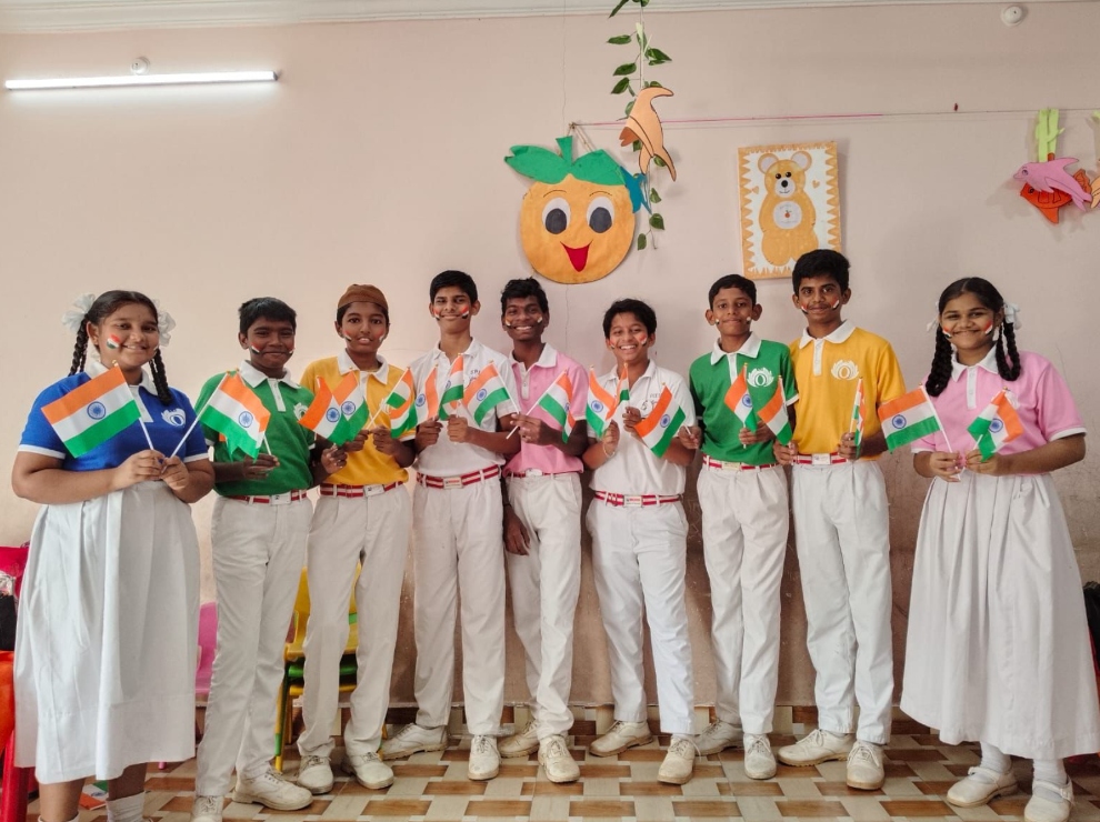 Group of students holding Indian national flags inside a classroom